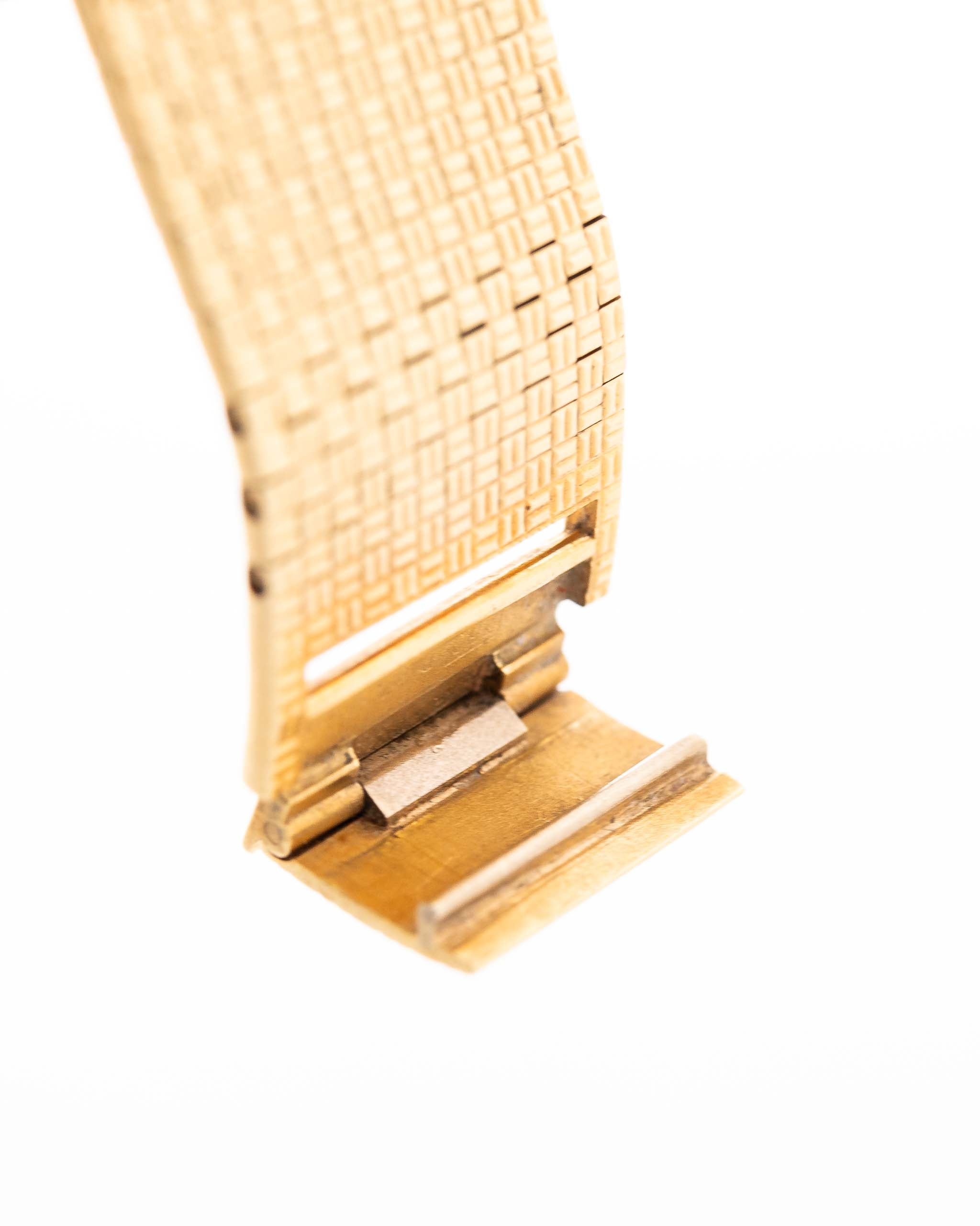 Closeup of Vintage Piaget Polo 7131 C5 bracelet. 23mm in 18k Yellow Gold with Guilloche Dial, Integrated 18k Gold Bracelet and Quartz Movement.