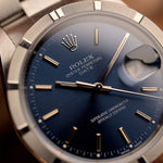 Rolex Oyster Perpetual 15210 Date watch with blue dial and stainless steel case on a blurred background