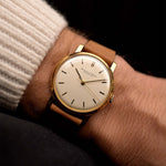 Vintage IWC Cal. 401 Dress Watch R1205 18k from 1964 on a wrist on black background. 33mm wide with 18k Yellow Gold Case, Manual Caliber 401 Movement, Flawless Silver Dial and Cognac Brown Leather Strap.