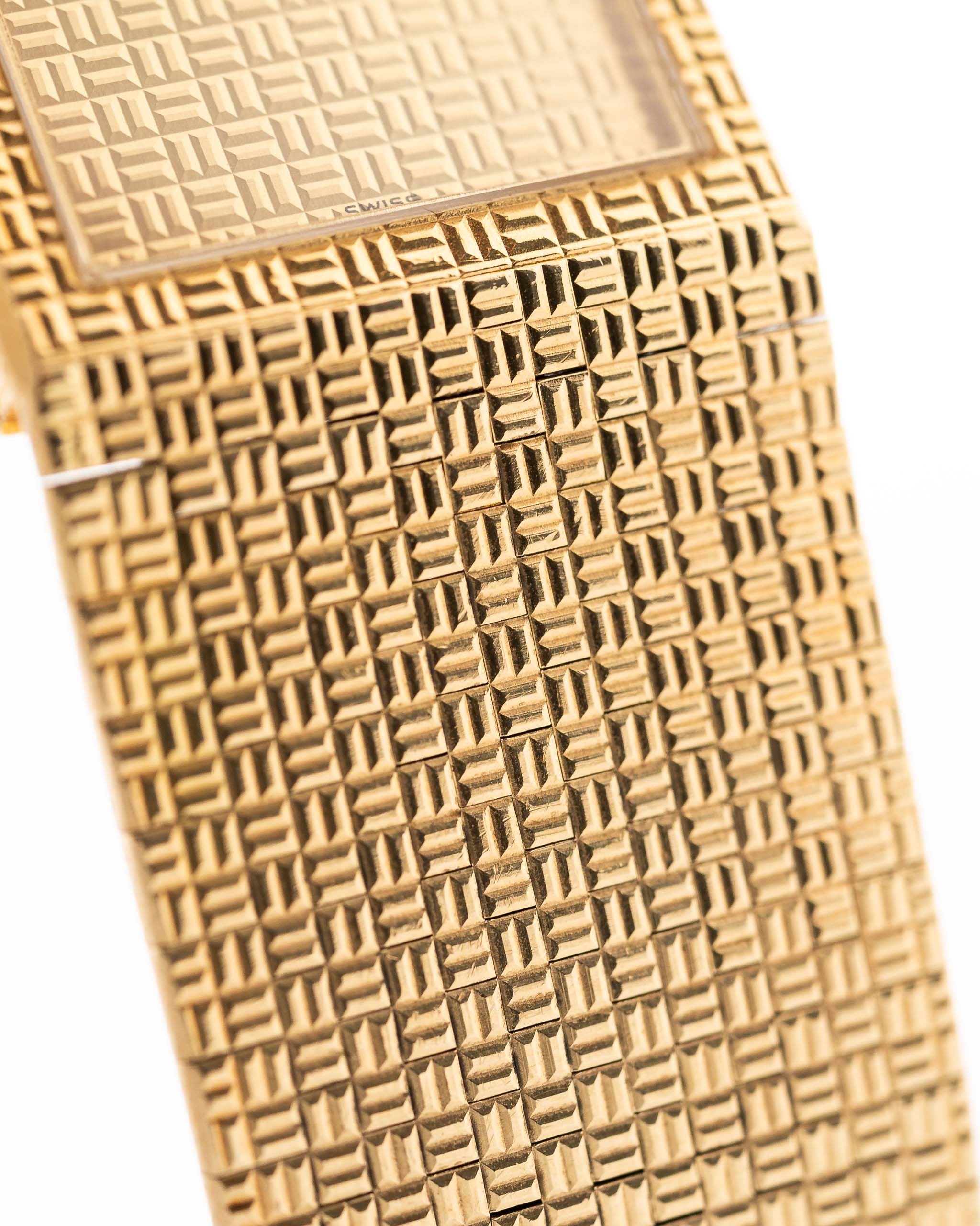 Nahaufnahme des Vintage Piaget Polo 7131 C5 Armbands. 23 mm aus 18k Gelbgold mit guillochiertem Zifferblatt, integriertem 18k Goldarmband und Quarzwerk.