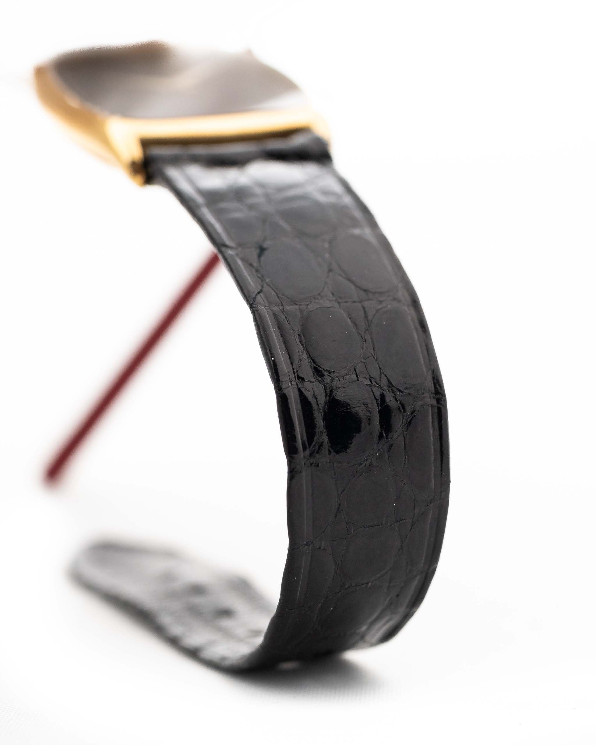 Nahaufnahme einer Piaget Tonneau 9691 Onyx 18k aus den 1970er Jahren. 24 mm mit Gehäuse aus 18k Gelbgold, Uhrwerk mit Handaufzug, schwarzem Onyx-Zifferblatt und schwarzem Original-Lederarmband.