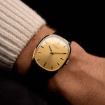 Goldene Vintage Patek Philippe Ellipse 3546 Uhr an einem Handgelenk aus den 1970er Jahren. 27 mm, Gehäuse aus 18 Karat Gelbgold, Handaufzugskaliber 23-300, makelloses goldenes Zifferblatt mit Sonnenschliff und schwarzes Lederarmband.