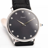 Primer plano de un Piaget Altiplano 9025 Gris 18k Vintage de los años 90. 33 mm en oro blanco de 18 quilates con movimiento de cuerda manual, esfera gris oscuro con efecto sol, índices con diamantes y correa de piel negra.