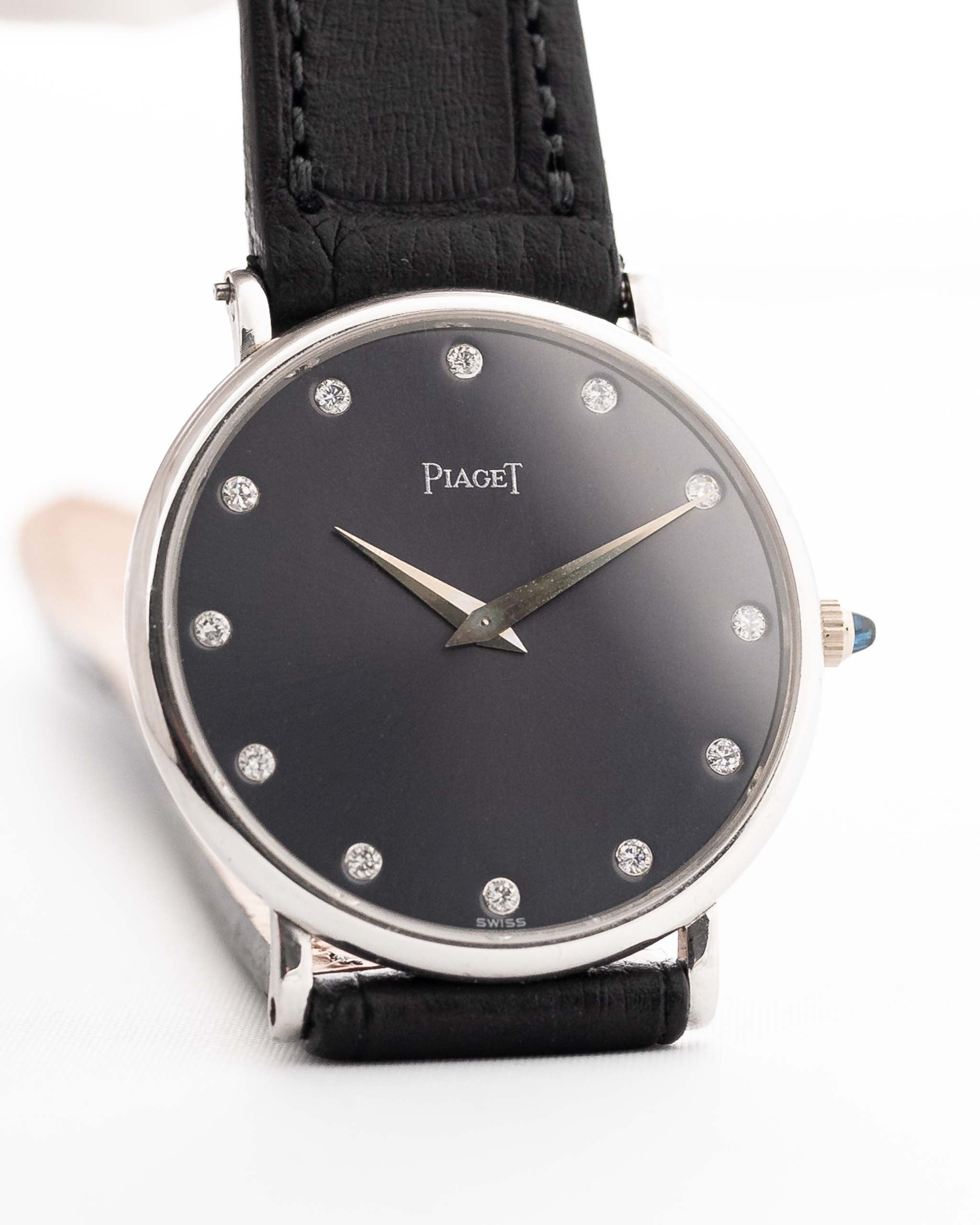 Primer plano de un Piaget Altiplano 9025 Gris 18k Vintage de los años 90. 33 mm en oro blanco de 18 quilates con movimiento de cuerda manual, esfera gris oscuro con efecto sol, índices con diamantes y correa de piel negra.