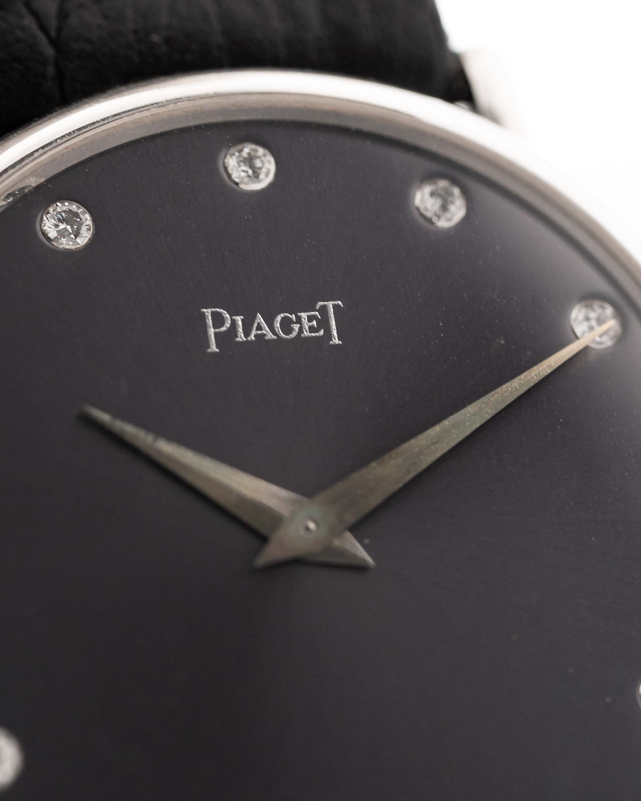 Primer plano de un Piaget Vintage Altiplano 9025 Esfera con Diamantes 18k Gris de los años 90. 33 mm en oro blanco de 18 quilates con movimiento de cuerda manual, esfera gris oscuro con efecto sol, índices con diamantes y correa de piel negra.