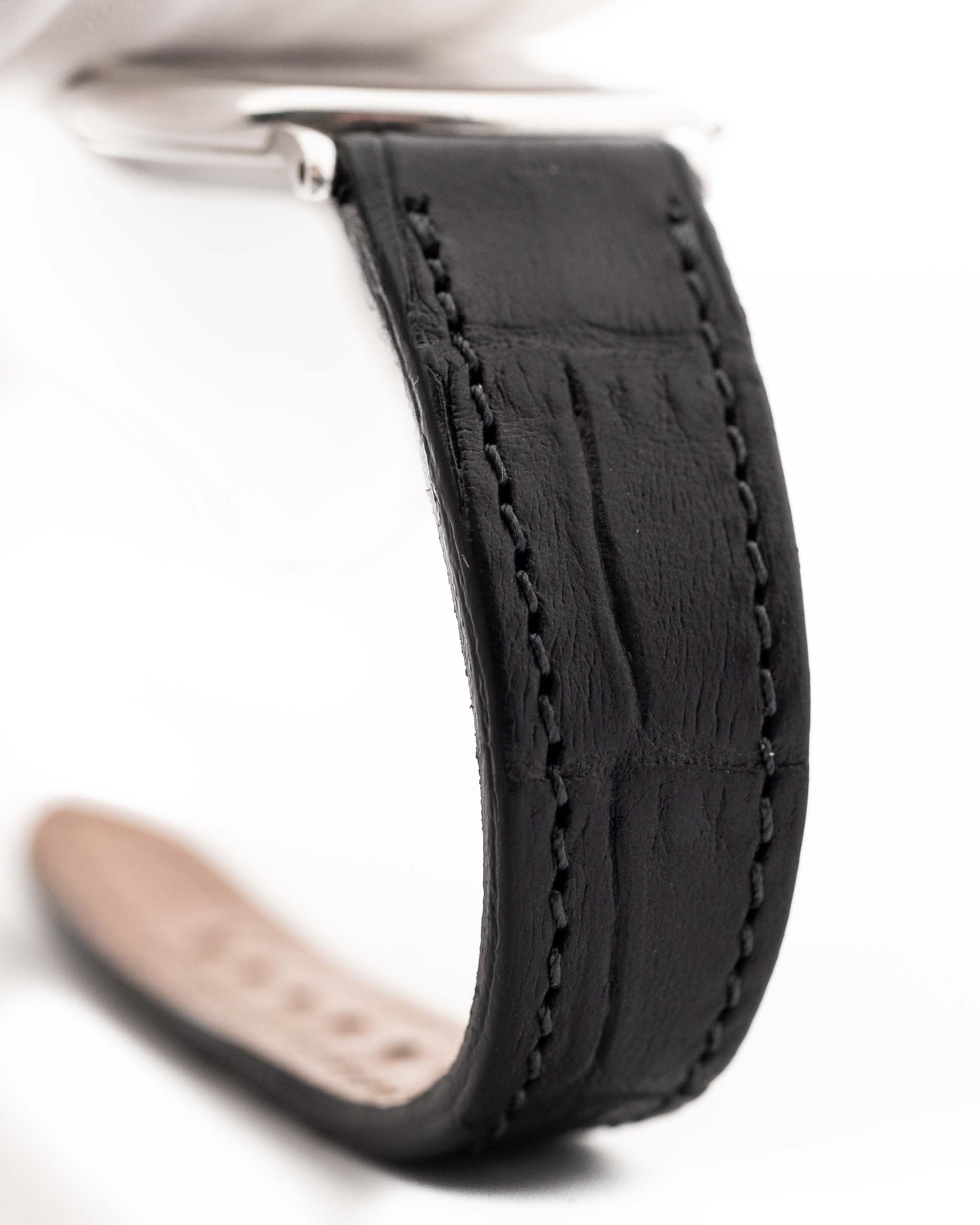 Primer plano de un Piaget Vintage Altiplano 9025 Caja con Diamantes 18k Gris de los años 90. 33 mm en oro blanco de 18 quilates con movimiento de cuerda manual, esfera gris oscuro con efecto sol, índices con diamantes y correa de piel negra.