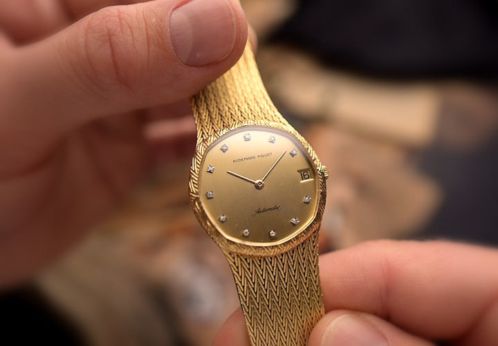 Reloj Audemars Piguet vintage de oro sostenido suavemente con ambas manos.