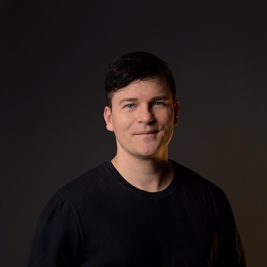 Hombre con camisa negra sobre fondo oscuro