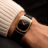 Montre Piaget Tonneau 9251 Onyx des années 1970 sur un poignet. 26mm avec boîtier en or jaune 18k, Calibre 9P à remontage manuel, cadran en onyx impeccable et bracelet en cuir d'origine.