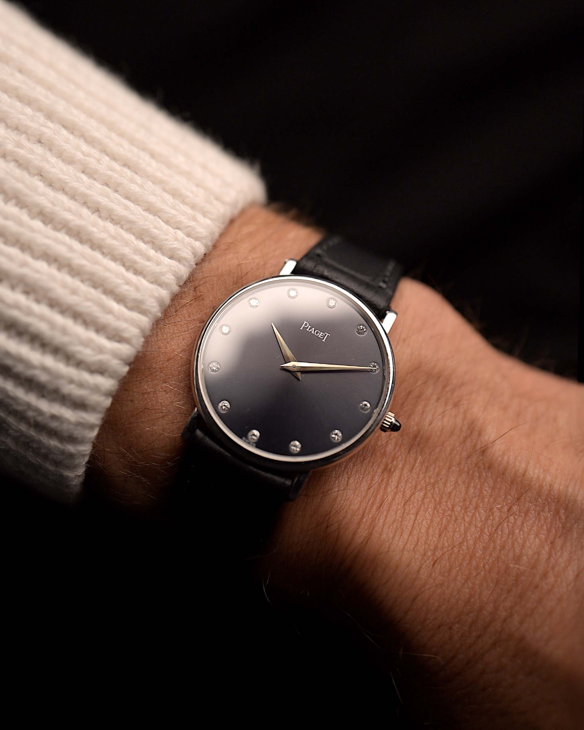 Piaget Altiplano 9025 Diamond 18k Grey des années 1990 sur un poignet. 33mm en or blanc 18k avec mouvement à remontage manuel, cadran gris foncé soleillé, index diamants et bracelet en cuir noir.