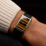 Montre Tank Piaget 9228 Tiger Eye des années 1970 sur un poignet. 34mm en or jaune 18k avec calibre 9P à remontage manuel, cadran original Tiger Eye et bracelet en cuir.