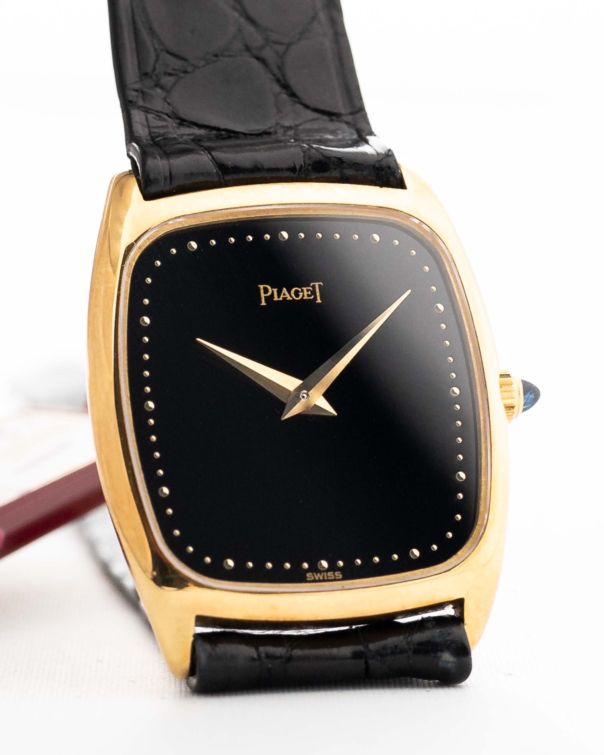 Photo en gros plan d'une Piaget Tonneau 9691 Onyx 18k des années 1970. 24mm avec boîtier en or jaune 18k, mouvement à remontage manuel, cadran en onyx noir et bracelet en cuir noir d'origine.