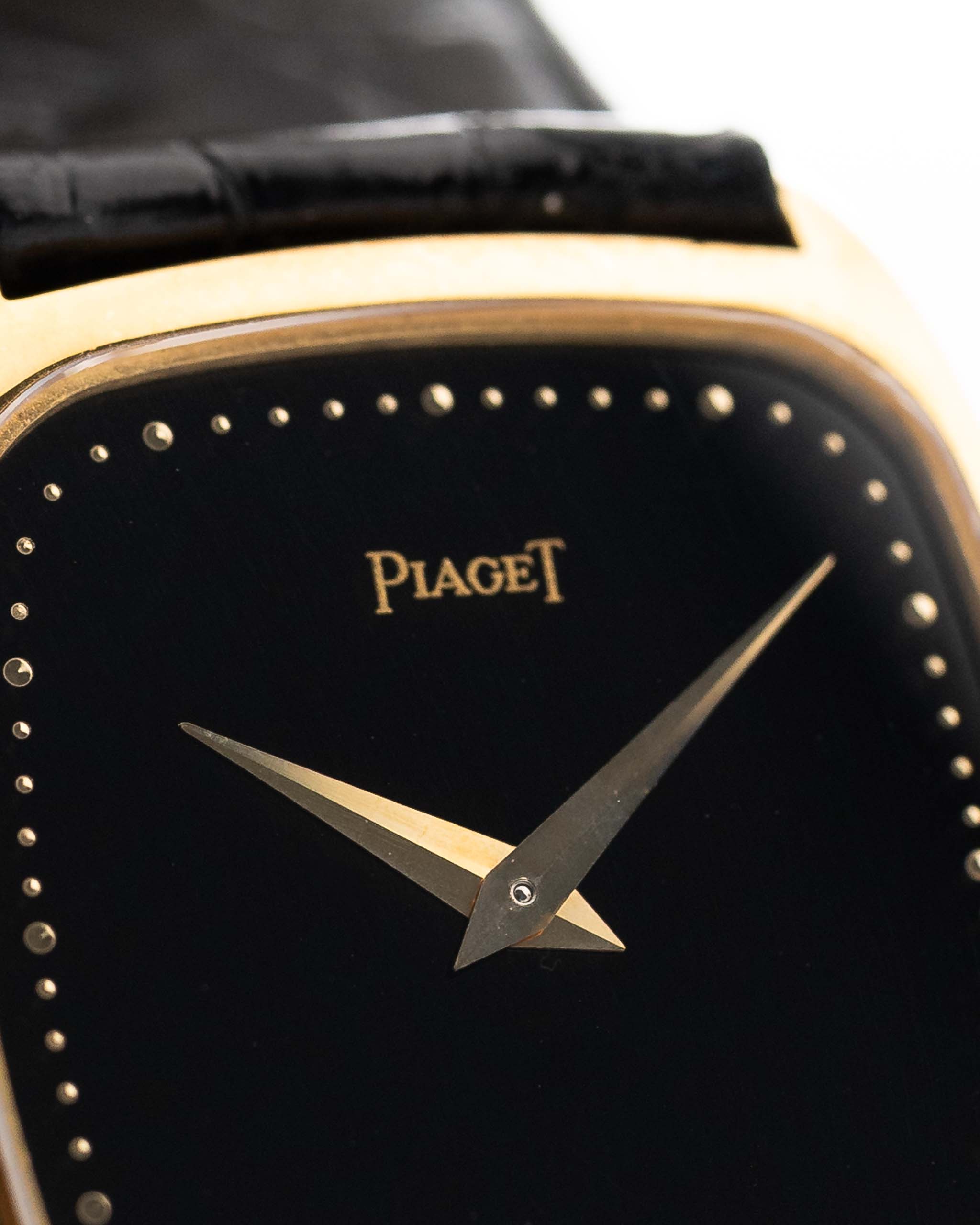 Photo en gros plan d'une Piaget Tonneau 9691 Onyx 18k des années 1970. 24mm avec boîtier en or jaune 18k, mouvement à remontage manuel, cadran en onyx noir et bracelet en cuir noir d'origine.