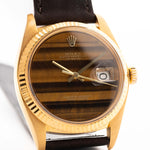 Photo en gros plan d'une Rolex Datejust 1601 Tiger Eye de 1974. 36mm avec boîtier en or jaune 18K, cadran en pierre Tiger Eye, mouvement automatique et bracelet en cuir.