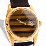 Photo en gros plan d'une Rolex Datejust 1601 Tiger Eye de 1974. 36mm avec boîtier en or jaune 18K, cadran en pierre Tiger Eye, mouvement automatique et bracelet en cuir.