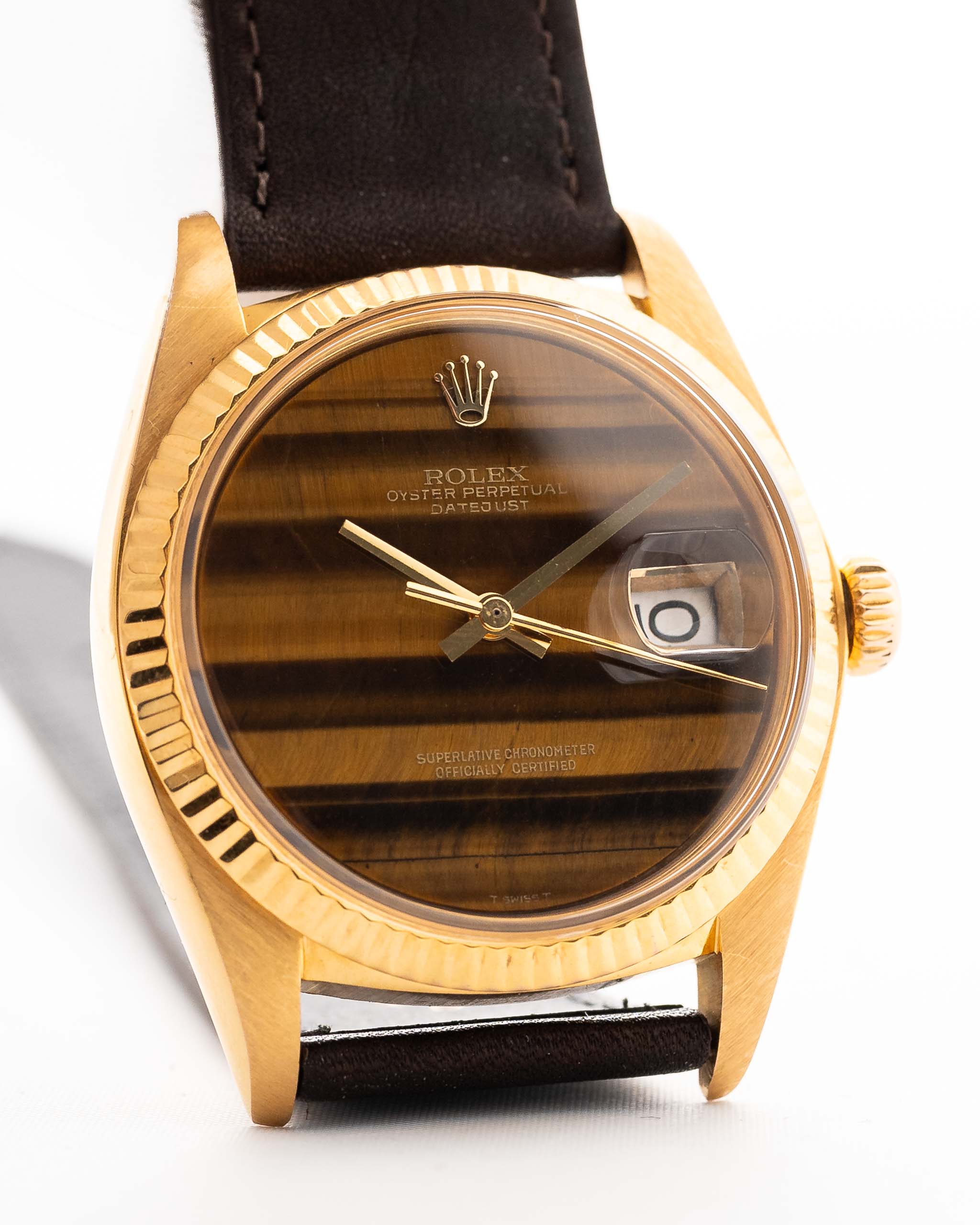 Photo en gros plan d'une Rolex Datejust 1601 Tiger Eye de 1974. 36mm avec boîtier en or jaune 18K, cadran en pierre Tiger Eye, mouvement automatique et bracelet en cuir.