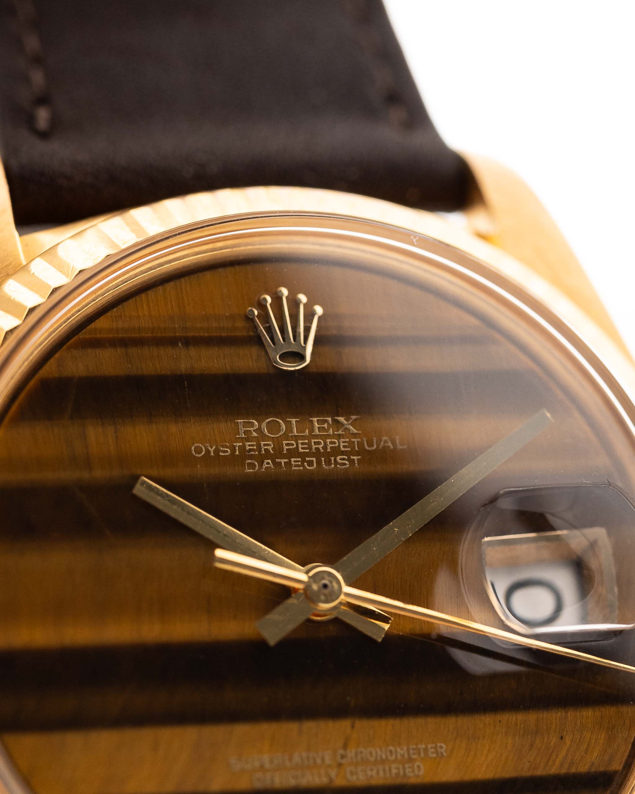 Photo en gros plan d'une Rolex Datejust 1601 Tiger Eye de 1974. 36mm avec boîtier en or jaune 18K, cadran en pierre Tiger Eye, mouvement automatique et bracelet en cuir.