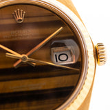 Photo en gros plan d'une Rolex Datejust 1601 Tiger Eye de 1974. 36mm avec boîtier en or jaune 18K, cadran en pierre Tiger Eye, mouvement automatique et bracelet en cuir.
