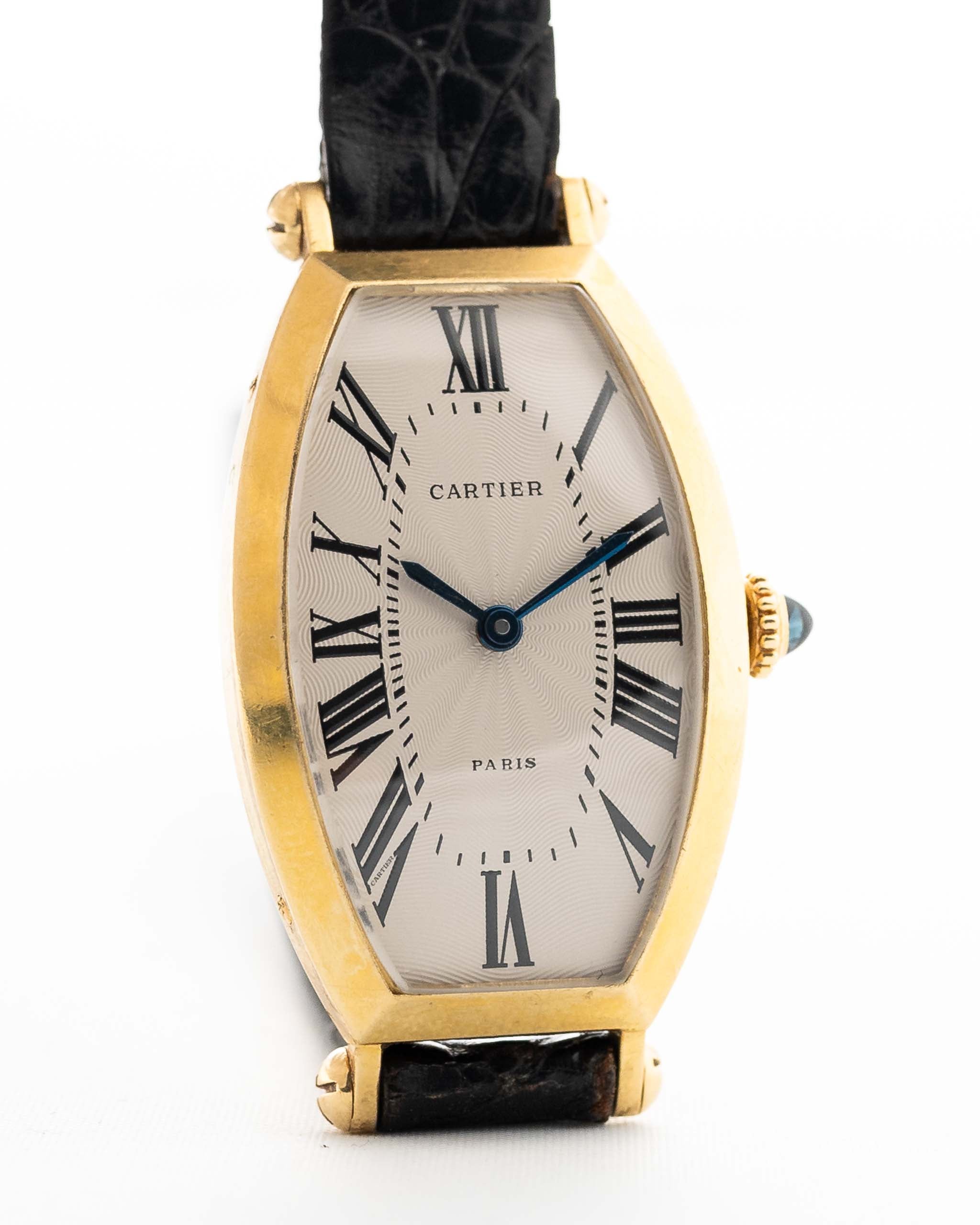 Foto ravvicinata di un Cartier Tonneau 18k Guilloché Paris vintage degli anni Ottanta. 39 mm con cassa in oro giallo 18k, movimento a carica manuale, quadrante originale Guilloché Paris e cinturino in pelle nera.