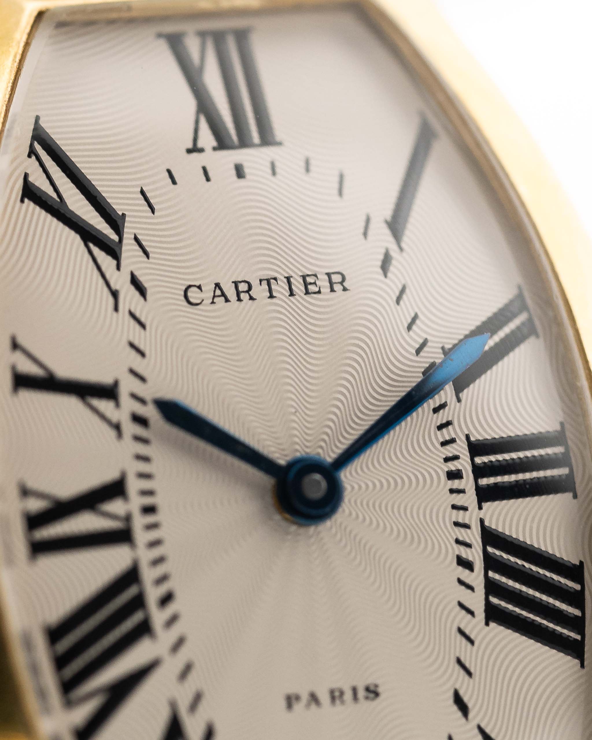 Foto ravvicinata di un quadrante Cartier Tonneau 18k Guilloché Paris vintage degli anni '80. 39 mm con cassa in oro giallo 18k, movimento a carica manuale, quadrante originale Guilloché Paris e cinturino in pelle nera.