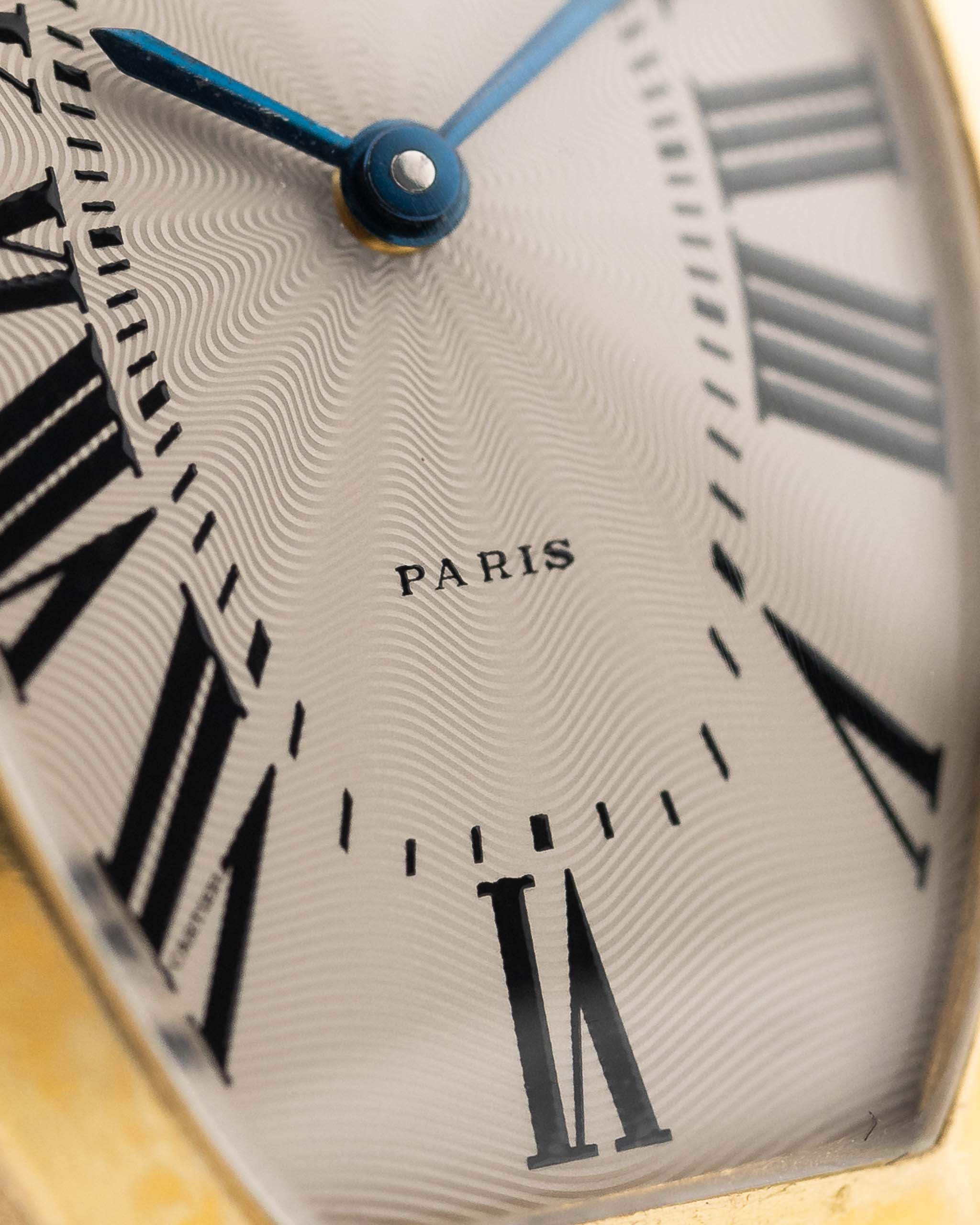 Foto ravvicinata di un quadrante Cartier Tonneau 18k Guilloché Paris vintage degli anni '80. 39 mm con cassa in oro giallo 18k, movimento a carica manuale, quadrante originale Guilloché Paris e cinturino in pelle nera.