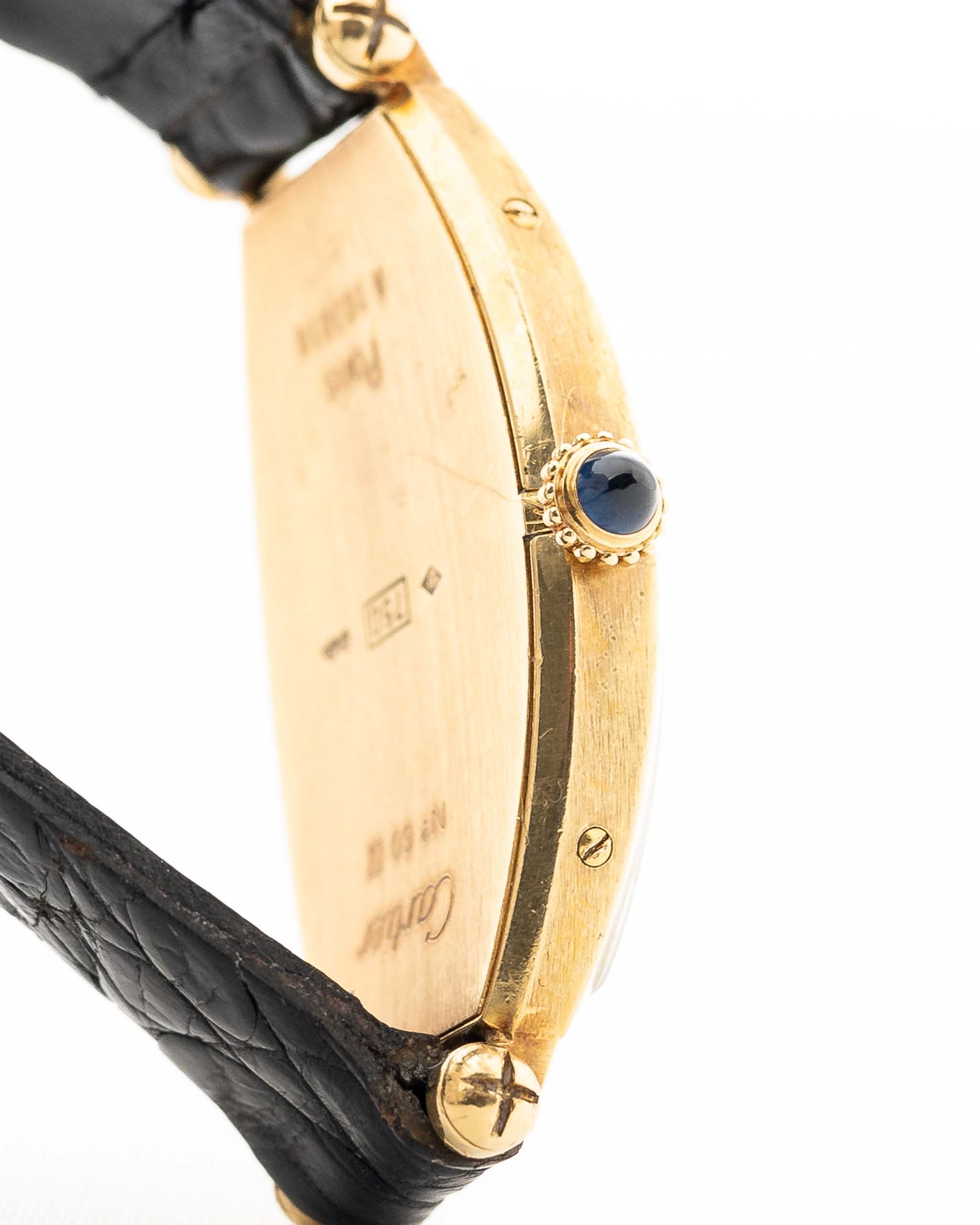 Foto ravvicinata di un Cartier Tonneau 18k Guilloché Paris vintage degli anni Ottanta. 39 mm con cassa in oro giallo 18k, movimento a carica manuale, quadrante originale Guilloché Paris e cinturino in pelle nera.