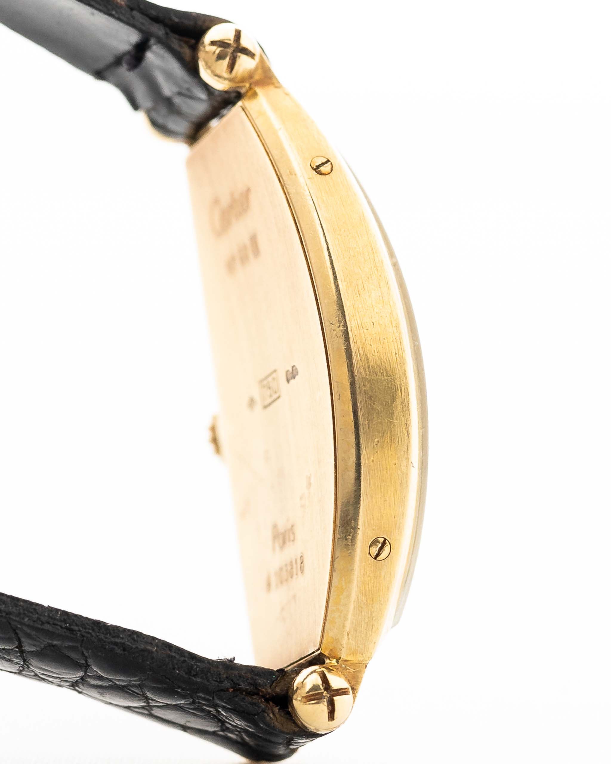 Foto ravvicinata di un Cartier Tonneau 18k Guilloché Paris vintage degli anni Ottanta. 39 mm con cassa in oro giallo 18k, movimento a carica manuale, quadrante originale Guilloché Paris e cinturino in pelle nera.