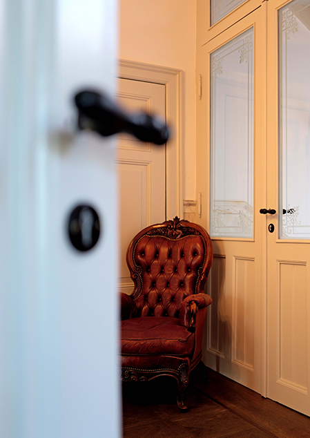 Poltrona decorativa in una stanza con pannelli in legno e porte rivestite in vetro.