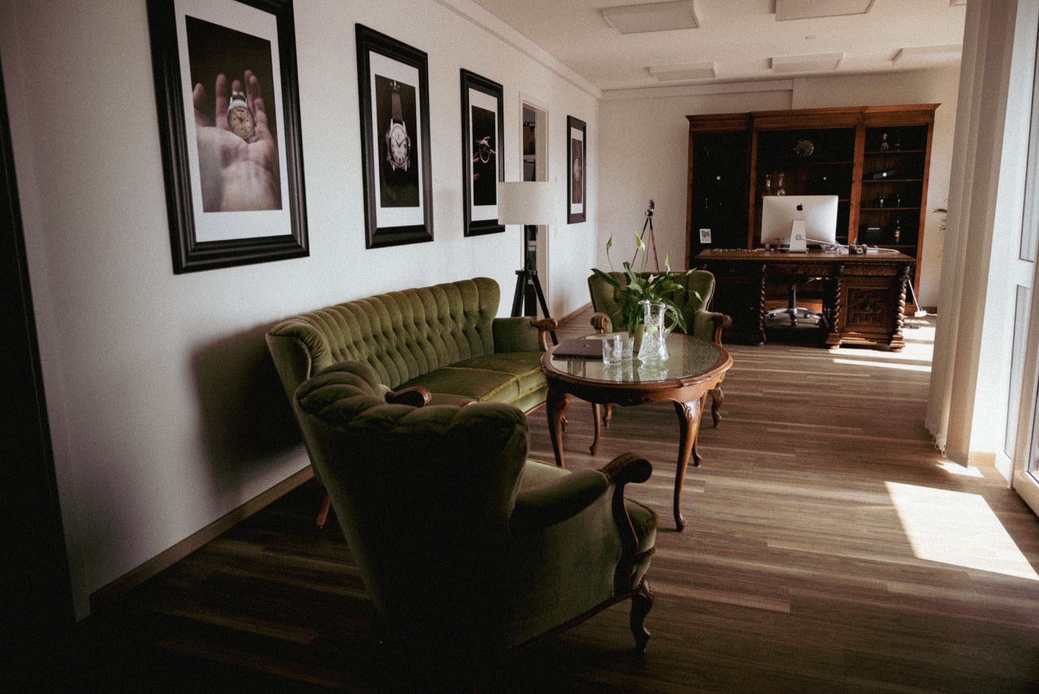 Lounge dell'ufficio con sedie verdi e foto incorniciate.