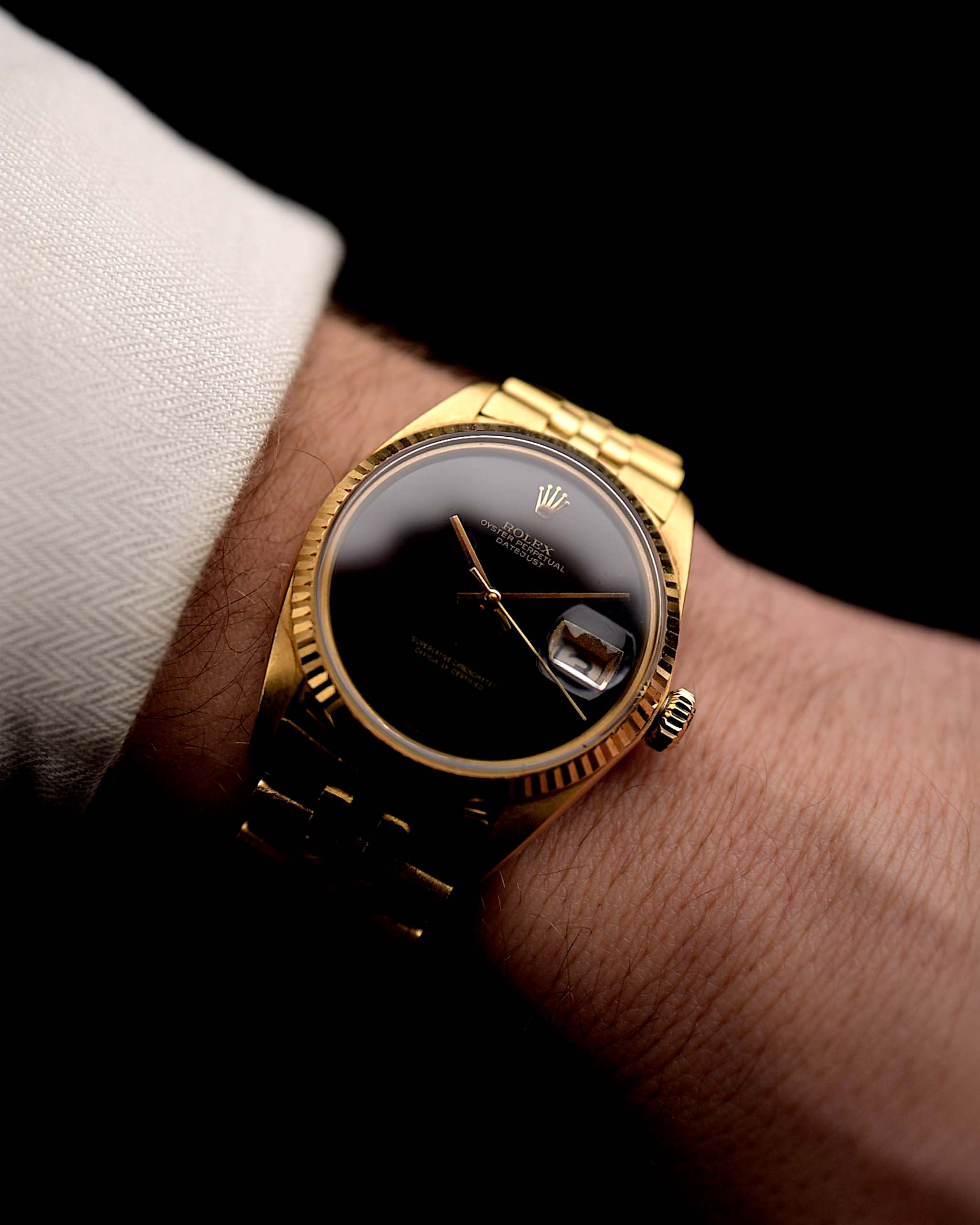Una foto di un Rolex Datejust 36 mm 1601 Onyx in oro giallo del 1969 su un polso. in oro giallo 18 carati con calibro automatico 157, quadrante originale in onice e bracciale Jubilee.
