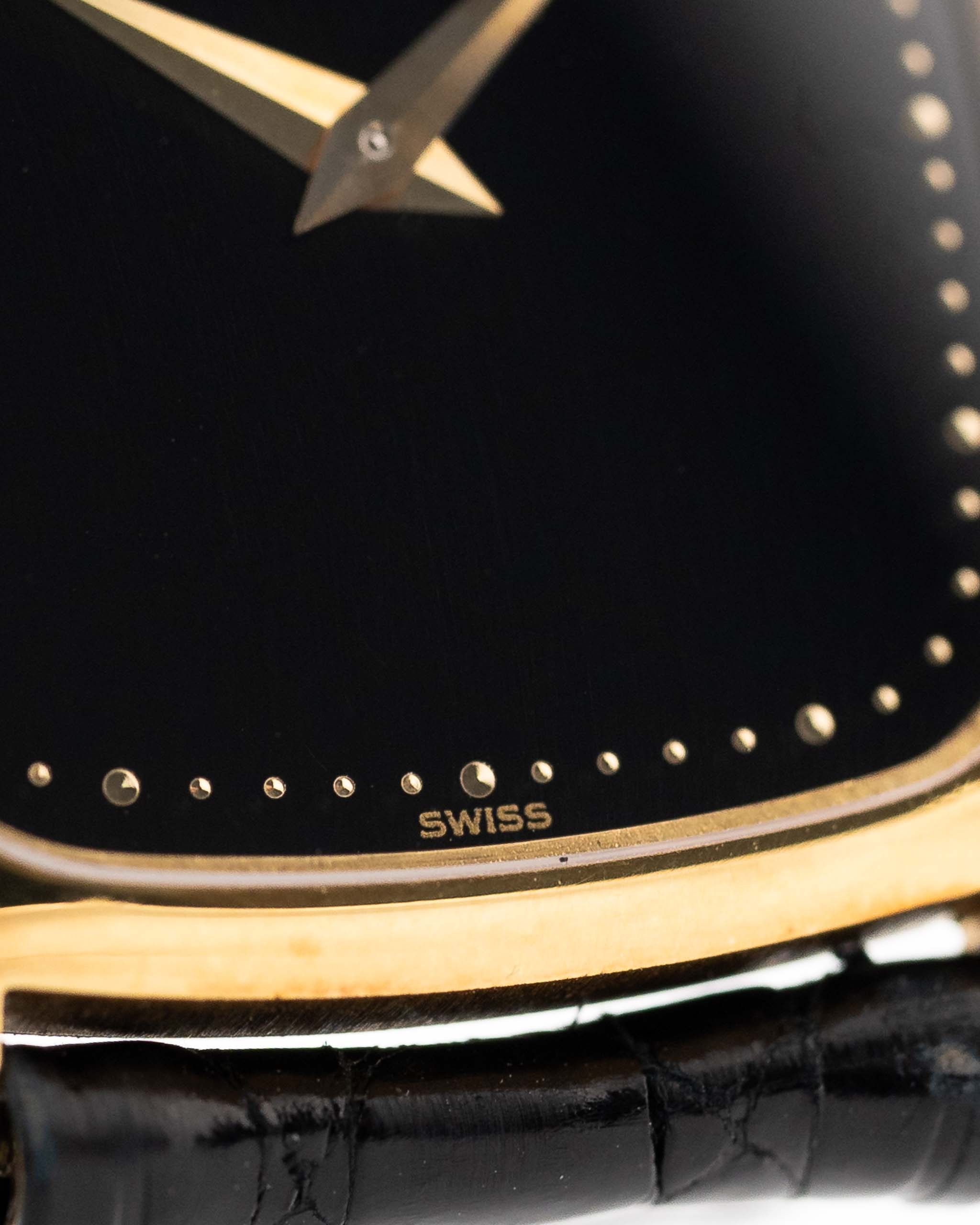 1970 年代 Piaget Tonneau 9691 Onyx 18K 手錶特寫照片。24mm 18K 黃金錶殼、手動上鏈機芯、黑色縞瑪瑙錶盤和原裝黑色真皮錶帶。