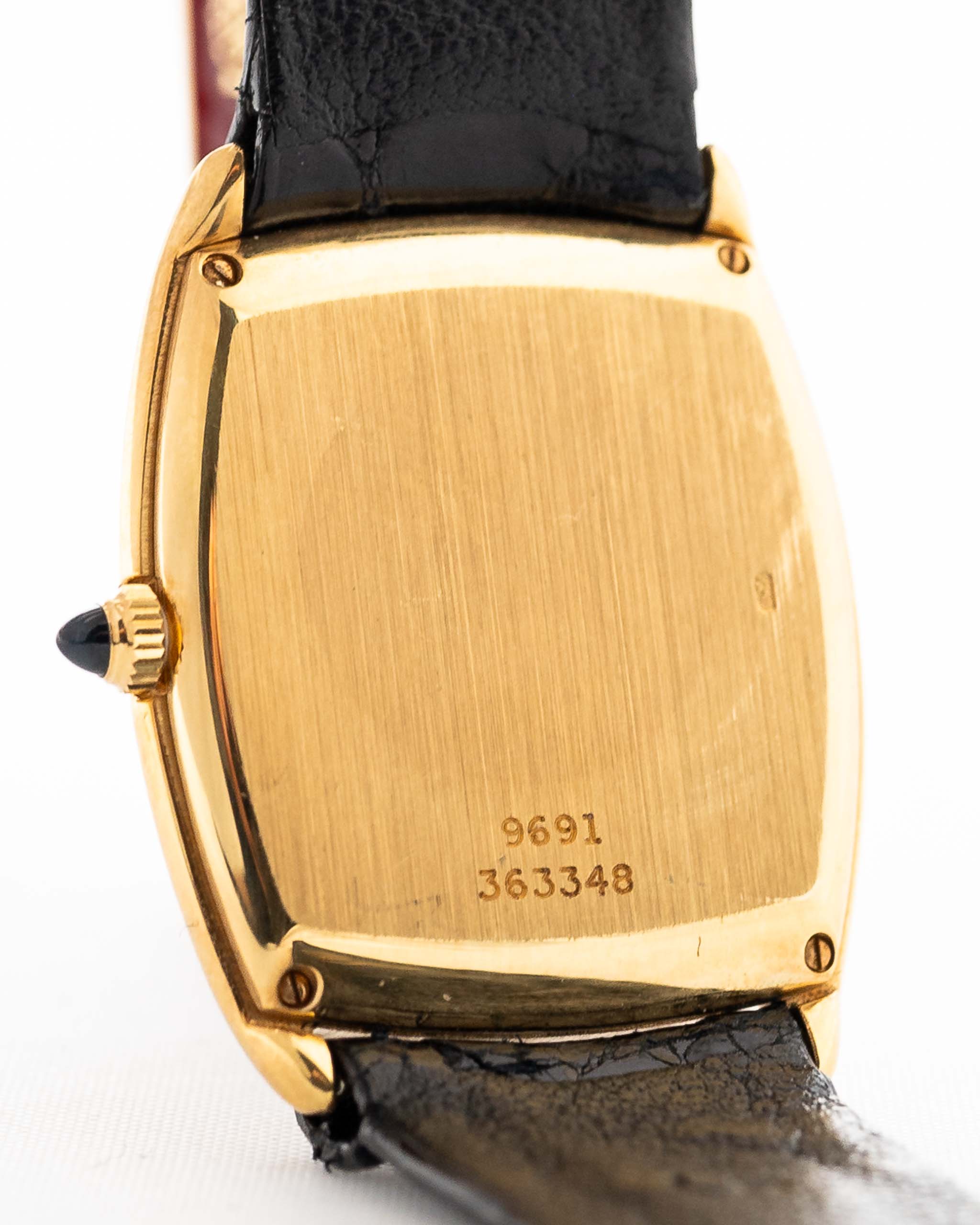 1970 年代 Piaget Tonneau 9691 Onyx 18K 手錶特寫照片。24mm 18K 黃金錶殼、手動上鏈機芯、黑色縞瑪瑙錶盤和原裝黑色真皮錶帶。