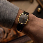 ساعة Vacheron Constantin 39007 Ellipse عتيقة من الذهب عيار 18 قيراط، بعلبة بيضاوية الشكل، وميناء رمادي، على معصم على خلفية ضبابية