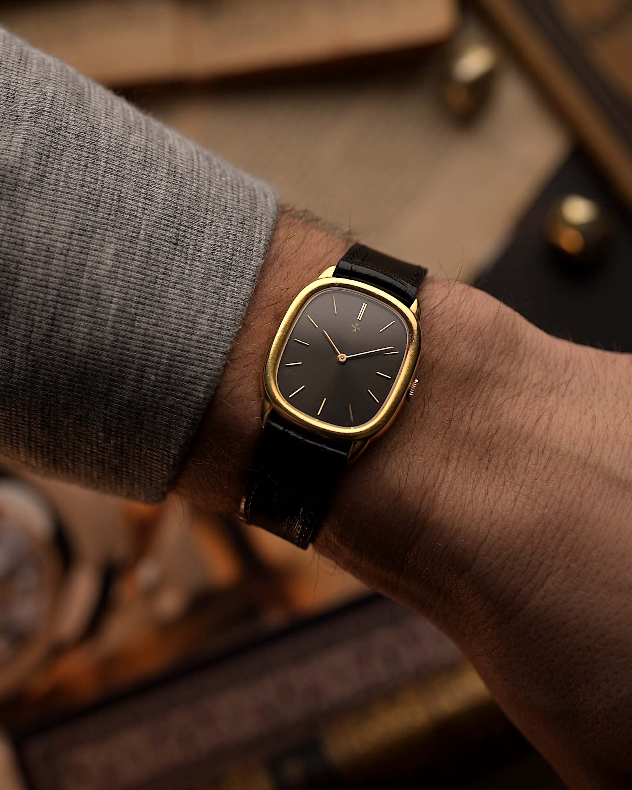 ساعة Vacheron Constantin 39007 Ellipse عتيقة من الذهب عيار 18 قيراط، بعلبة بيضاوية الشكل، وميناء رمادي، على معصم على خلفية ضبابية