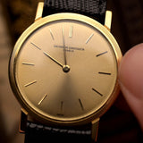ساعة Vacheron Constantin Patrimony 6351 عتيقة ذات علبة مستديرة رفيعة من الذهب عيار 18 قيراطًا، تُحمل بيد على خلفية ضبابية