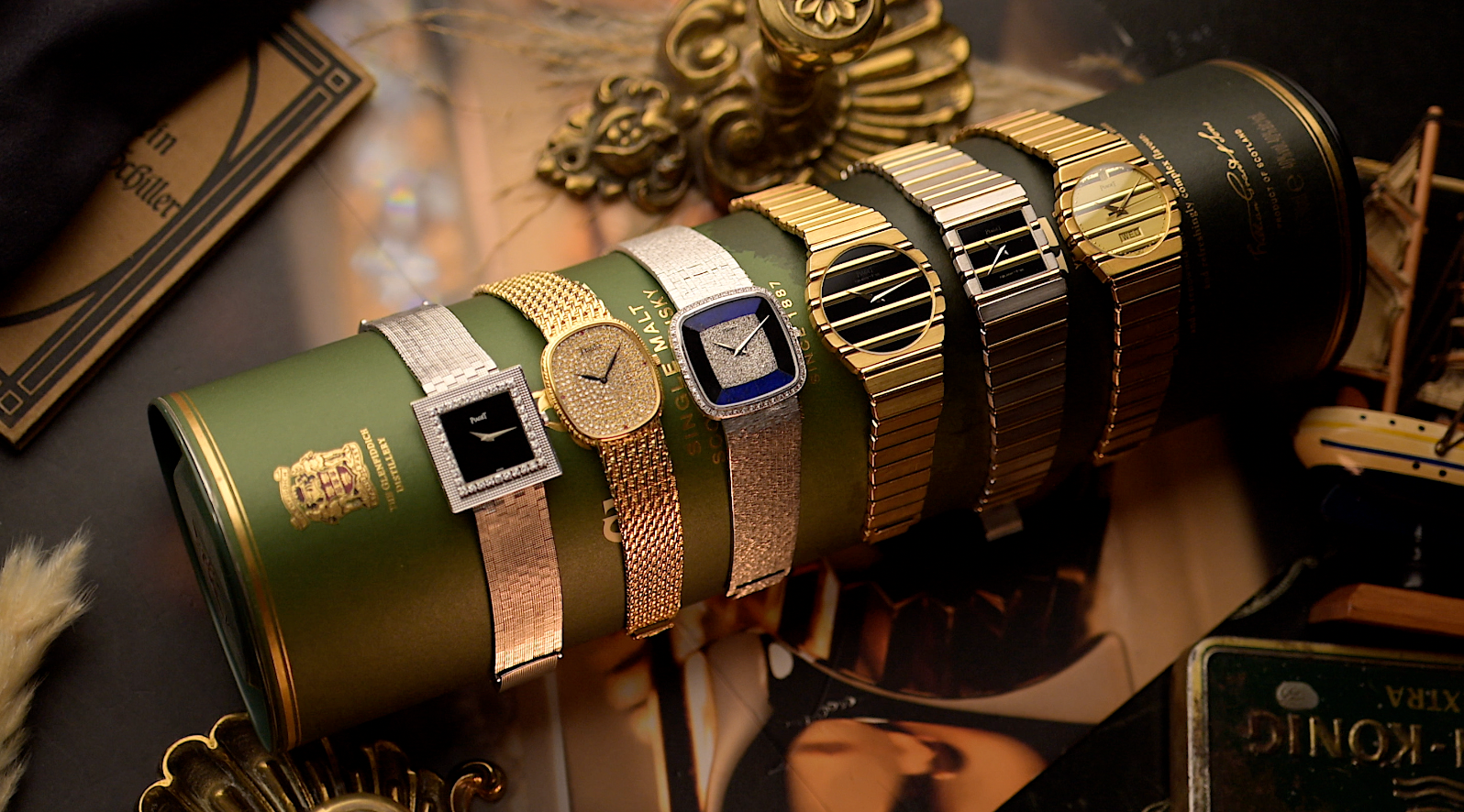 Vintage gold watches displayed on a green cylindrical case