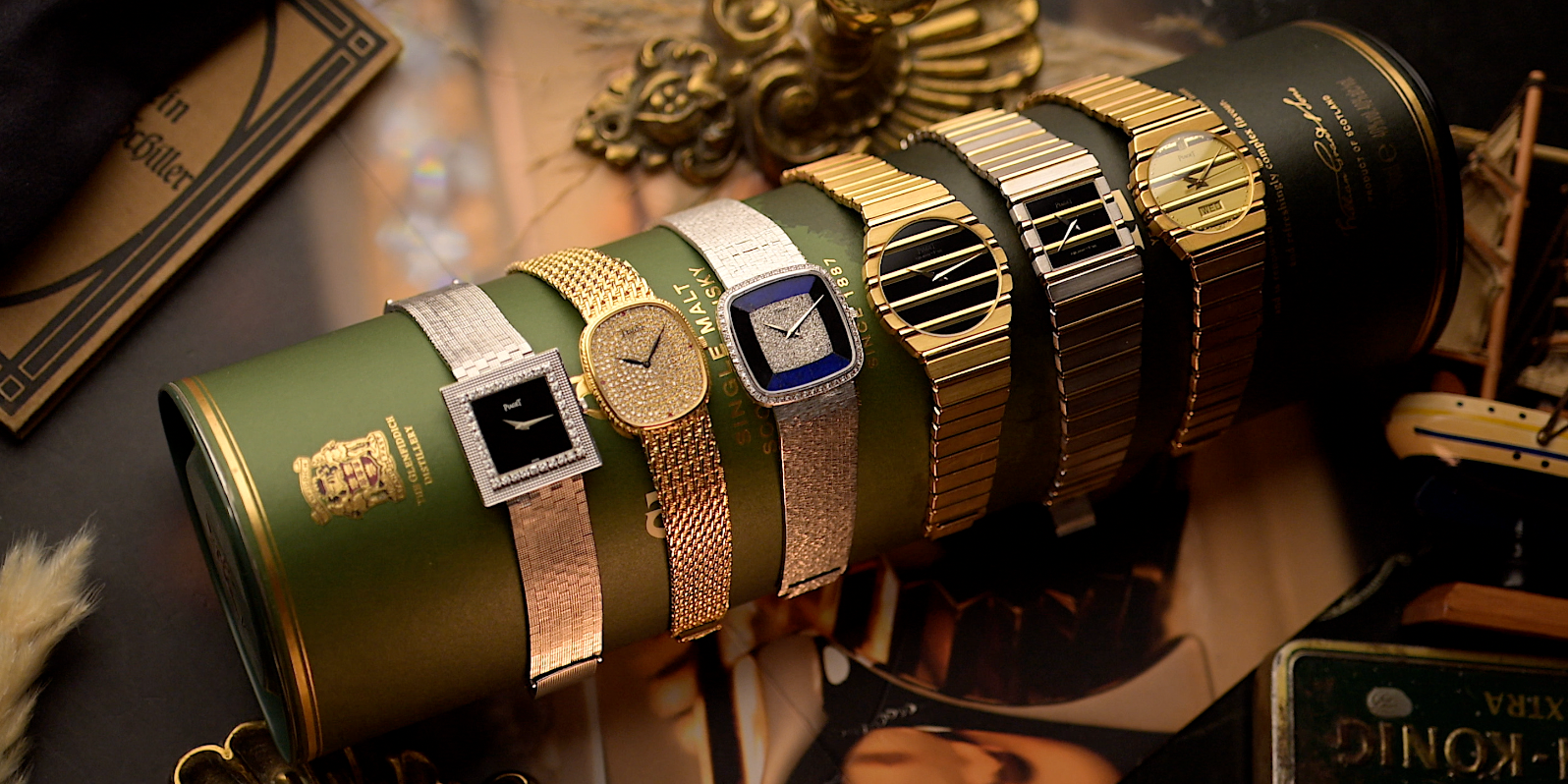 Vintage gold watches displayed on a green cylindrical case