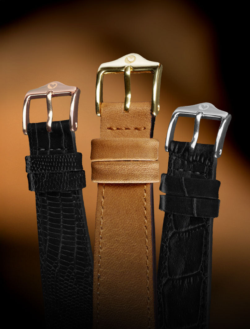Three leather watch straps with different metal buckles on a blurry brown background