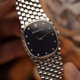 Vintage Audemars Piguet Cobra watch, 18k white gold, night blue diamond dial, manual movement, white gold bracelet, held by a hand against a blurred background