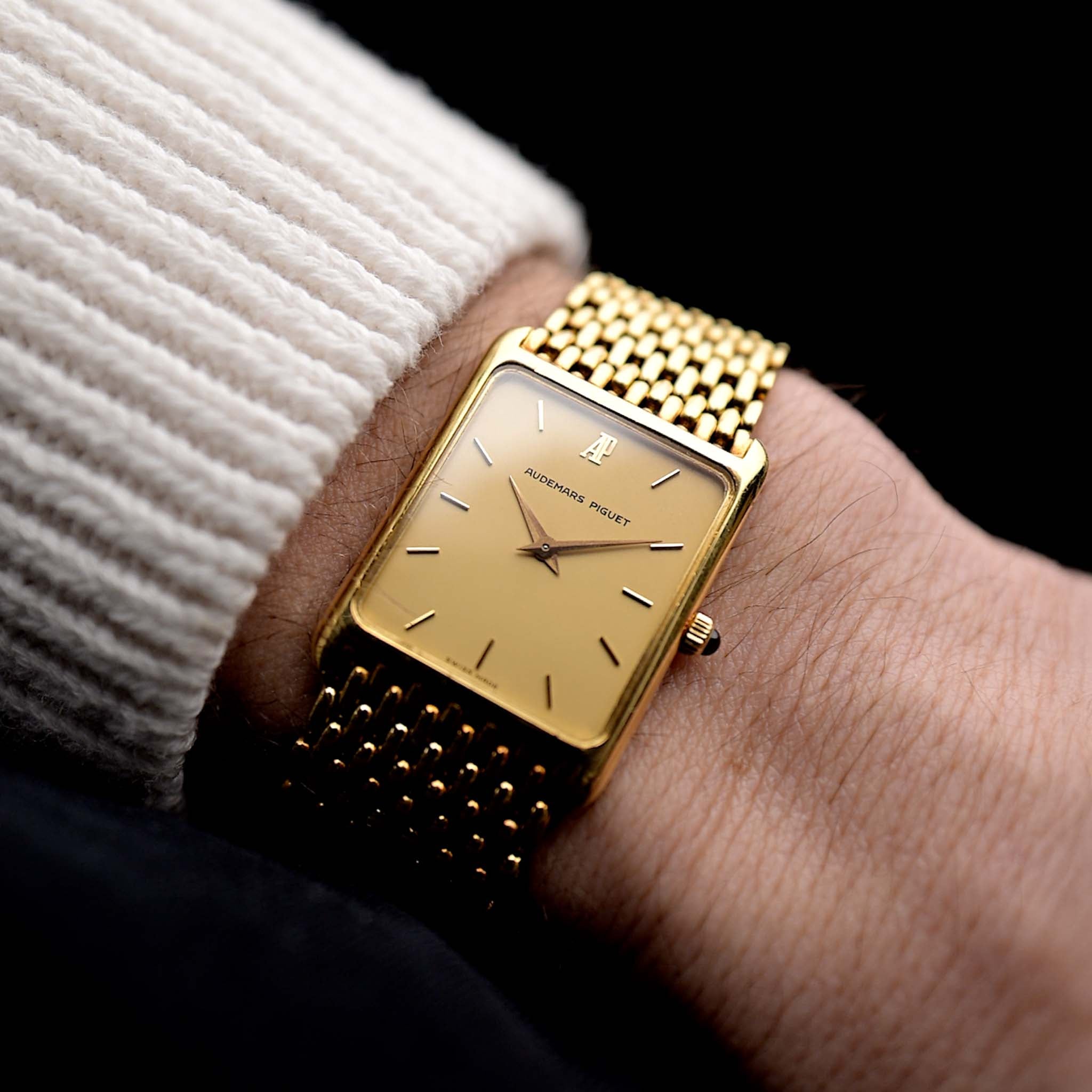 Photo of a Audemars Piguet 18k Tank from the 1980s on a wrist. 25mm case in 18k Yellow Gold with Manual wind movement, Original golden dial, Hands with sapphire cabochon and Beads of rice bracelet.