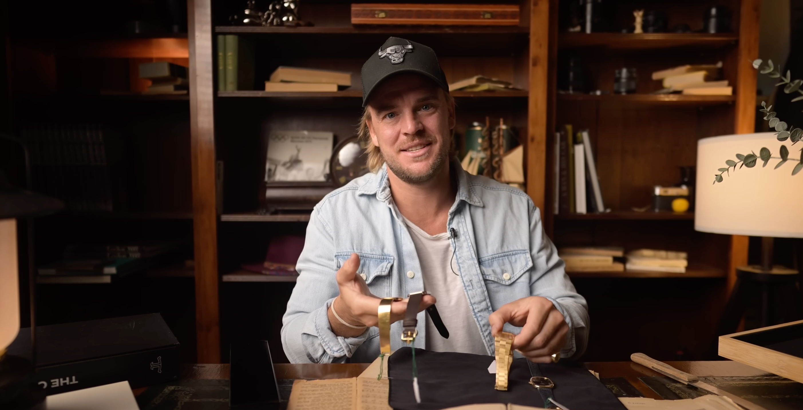 Man holding a small object in a room with shelves and books
