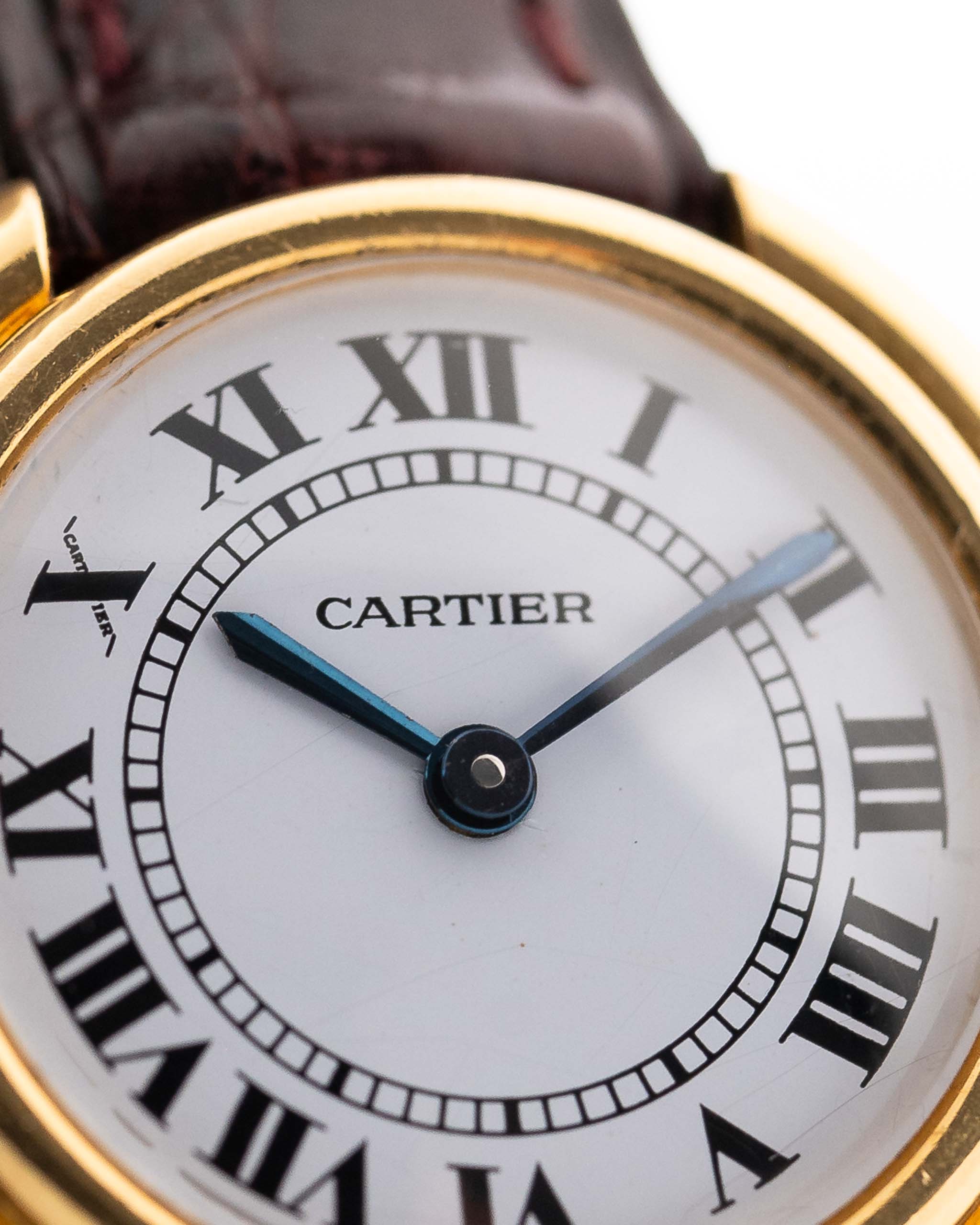 Close up of a Vintage Cartier Ellipse watch in 18k gold, white dial with Paris signature. white background