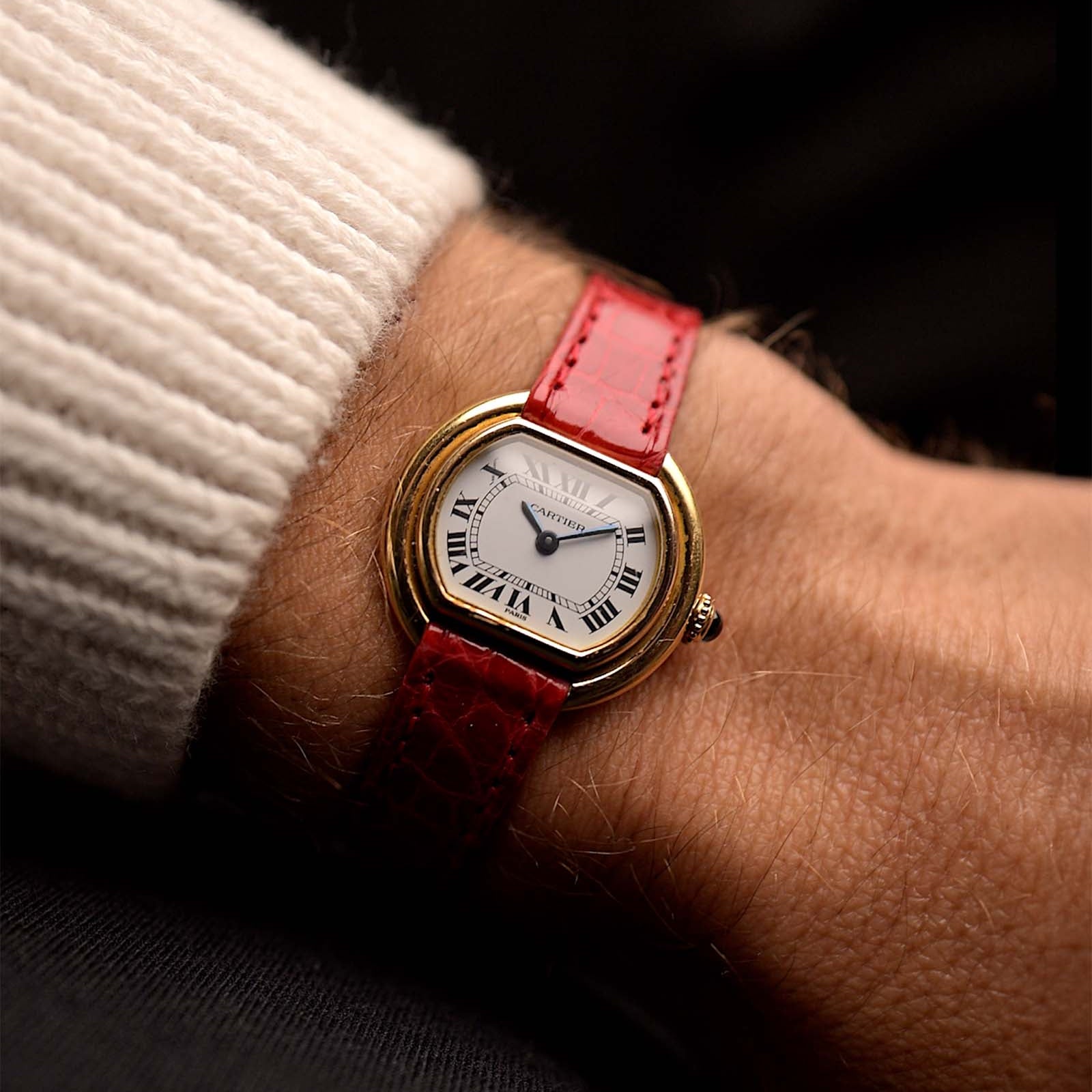Vintage Cartier Ellipse 67081 Watch 18k from the 1980s on a wrist. 26mm with 18k Yellow Gold case, Manual wind movement, Paris-signed dial, Blued steel hands and Red Leather strap.