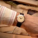 Rosegold Vintage Jaeger LeCoultre 18k Rose Railroad watch from the 1950s on a person's wrist with a beige background.