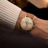 Longines 7414 chronograph, 18k gold with silver sunburst dial, worn on the wrist over a backdrop