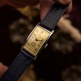 Omega T17 Art Deco vintage watch, golden dial and blued hands close-up, rectangular steel