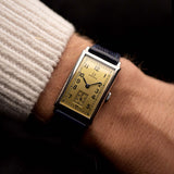 Omega T17 Art Deco vintage watch, steel case, golden dial, Arabic numerals, worn on the wrist