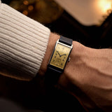 Omega T17 Art Deco, steel with golden dial, worn on the wrist over a warm backdrop
