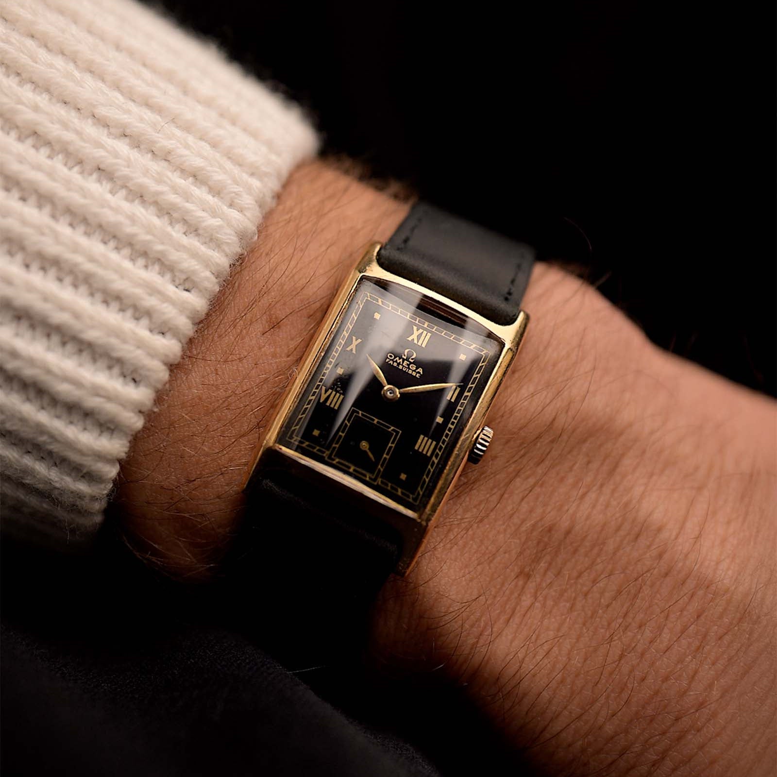 Vintage Omega Tank Gilt watch Roman from 1944 on a wrist. 18mm wide with 18k Rose Gold Case, Manual Wind Movement, Black Gilt Dial, Roman Numerals and Black Leather Strap.