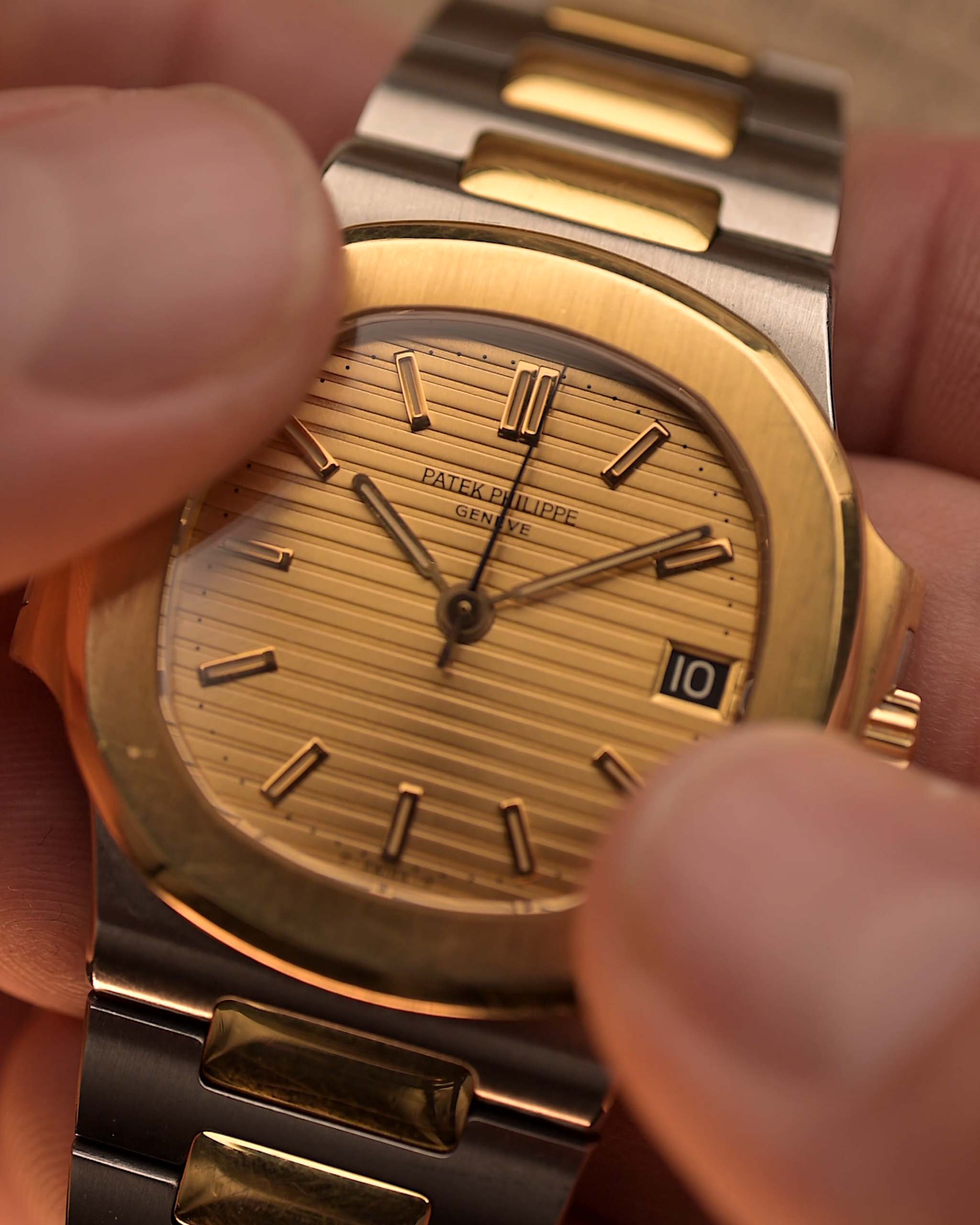 Vintage Patek Philippe Nautilus 3800 watch in two-tone gold and stainless steel, golden ribbed dial, automatic movement, held in hands